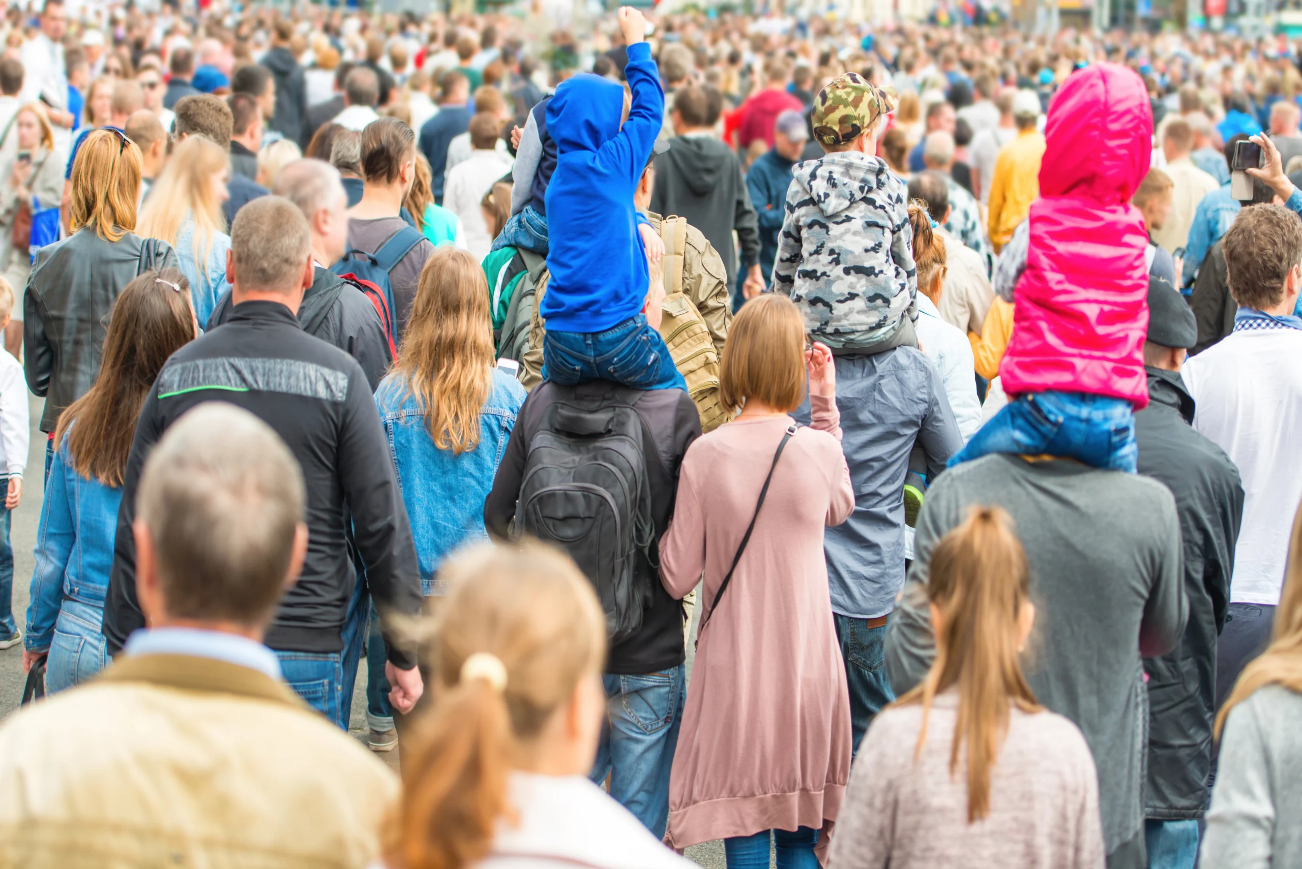 Event attendees, including children and families, walking through busy street during an outdoor event