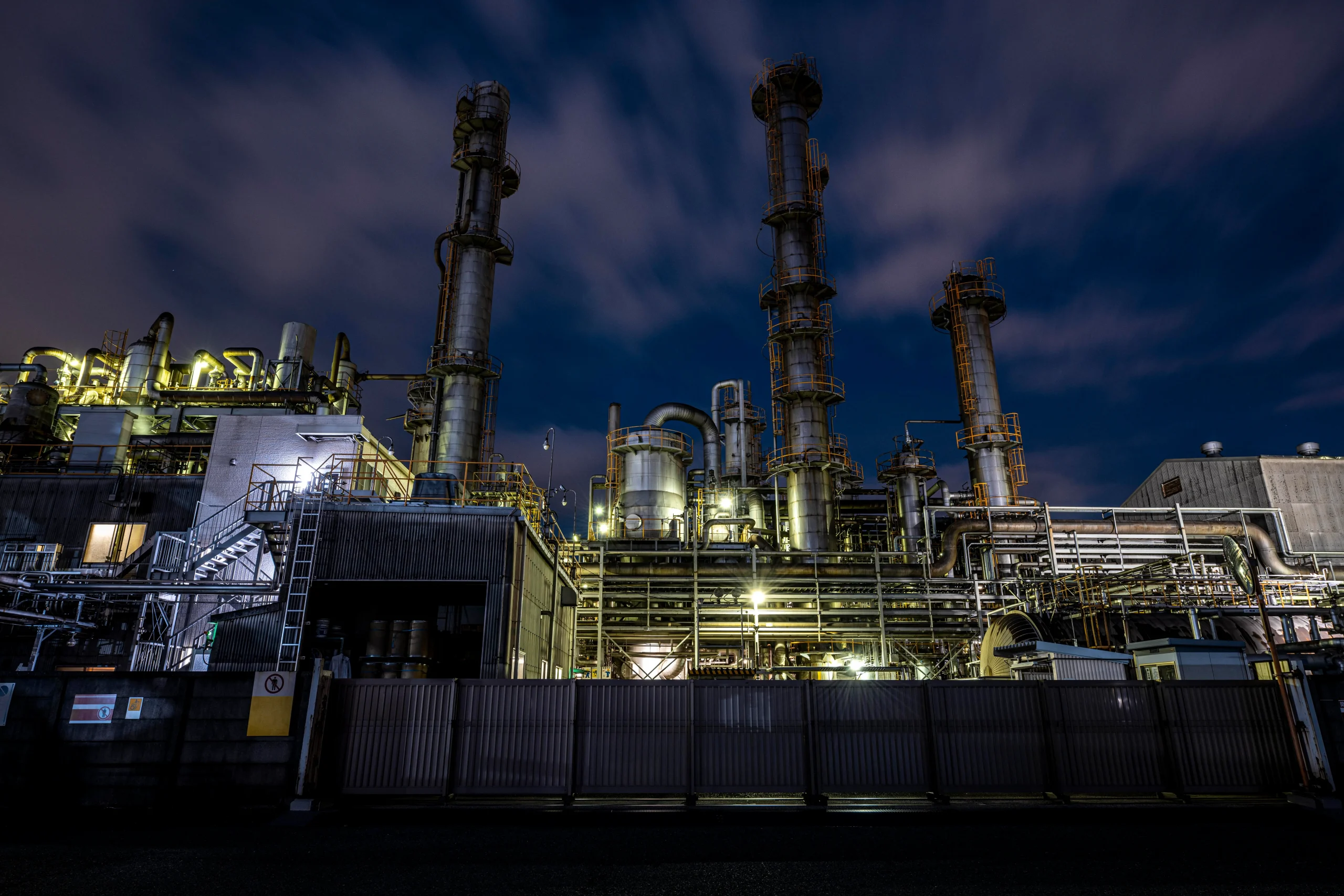 Exterior of factory at night with scattered clouds and minimal lighting 