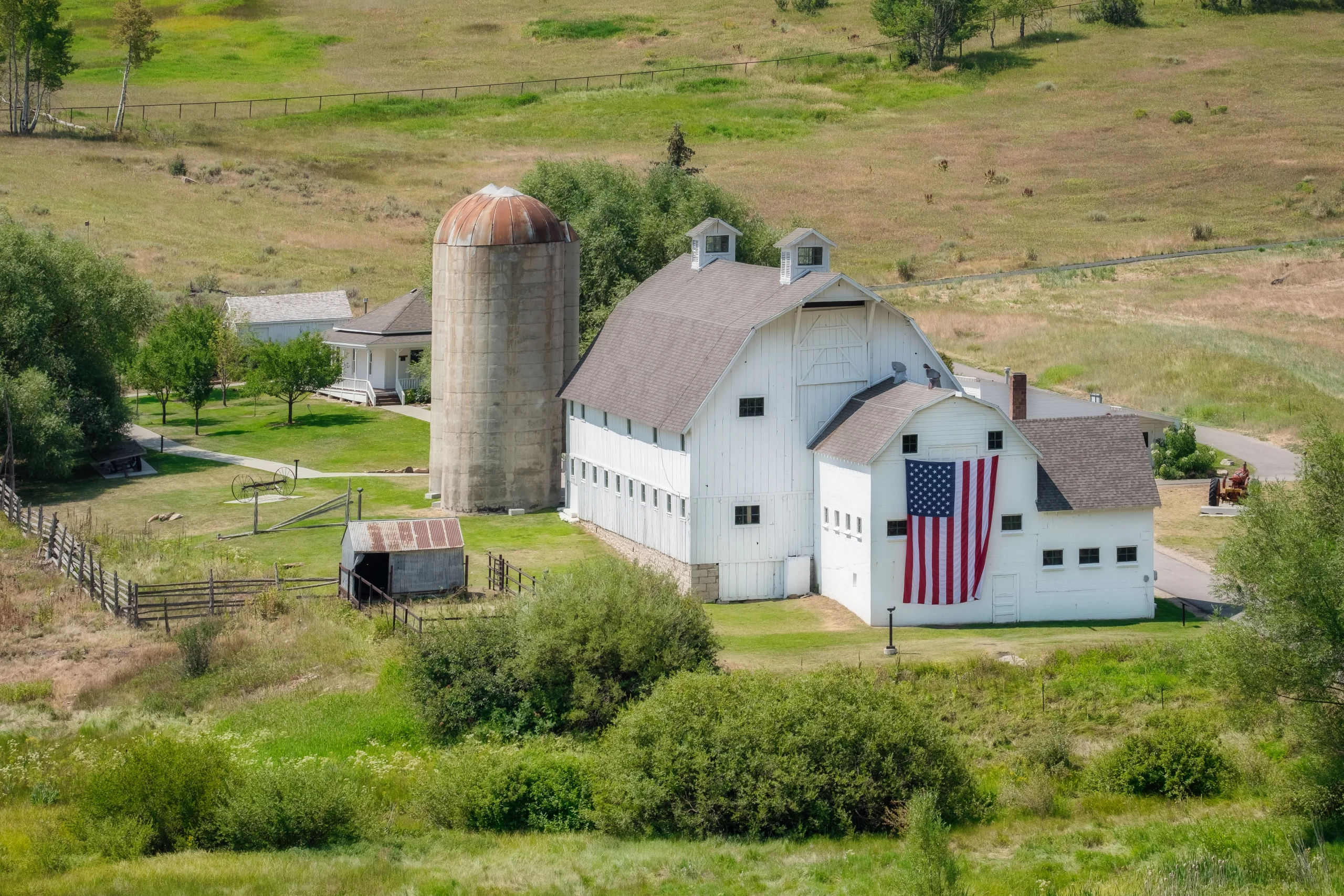White barn with flag of the United States on the side wall in green farmland area