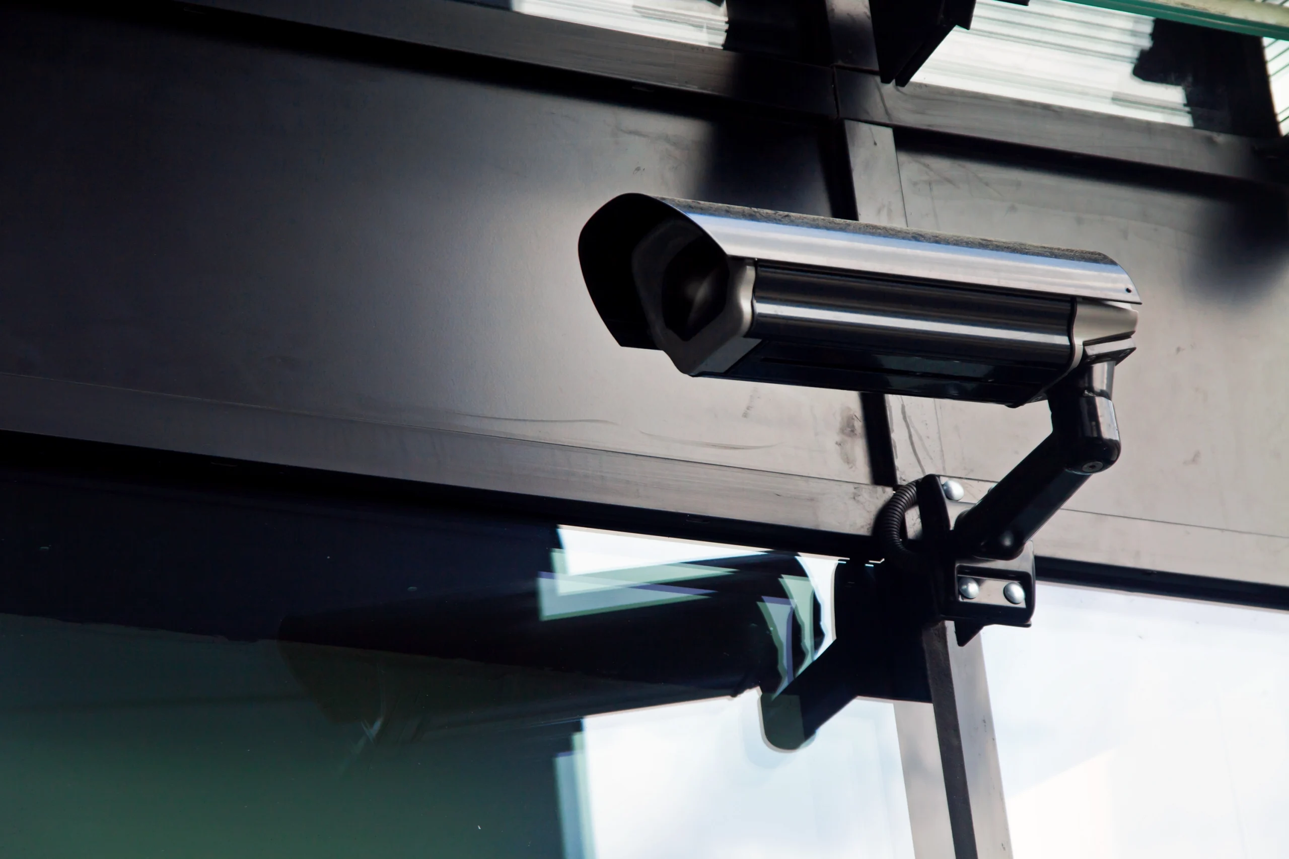 A CCTV camera positioned on the outside of an office building near the widnow looking across the premsies