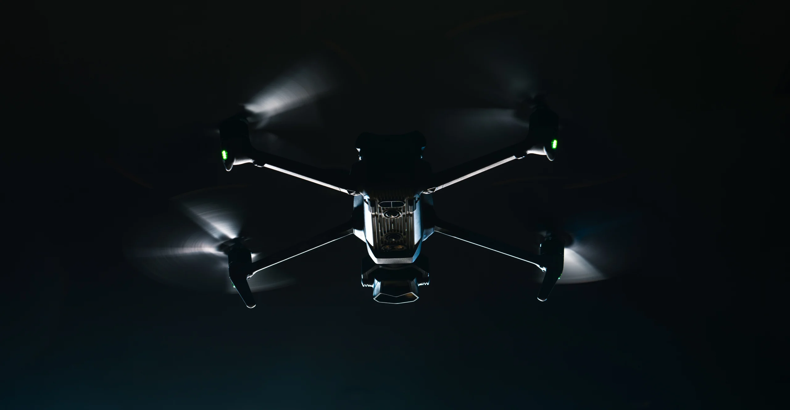 Black security drone with lighting on it flying at night with pitch black background