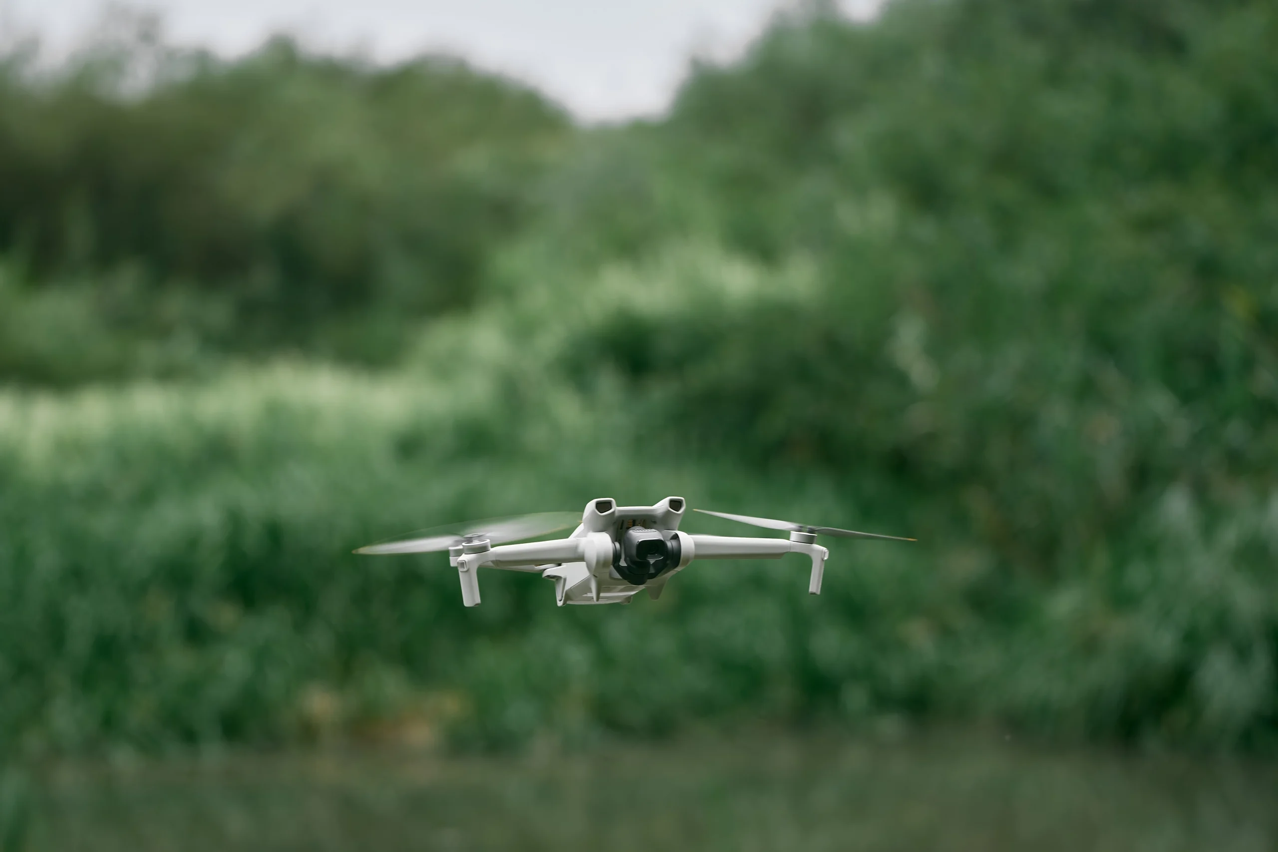 White search and rescue drone flying across dense forest with tress in background