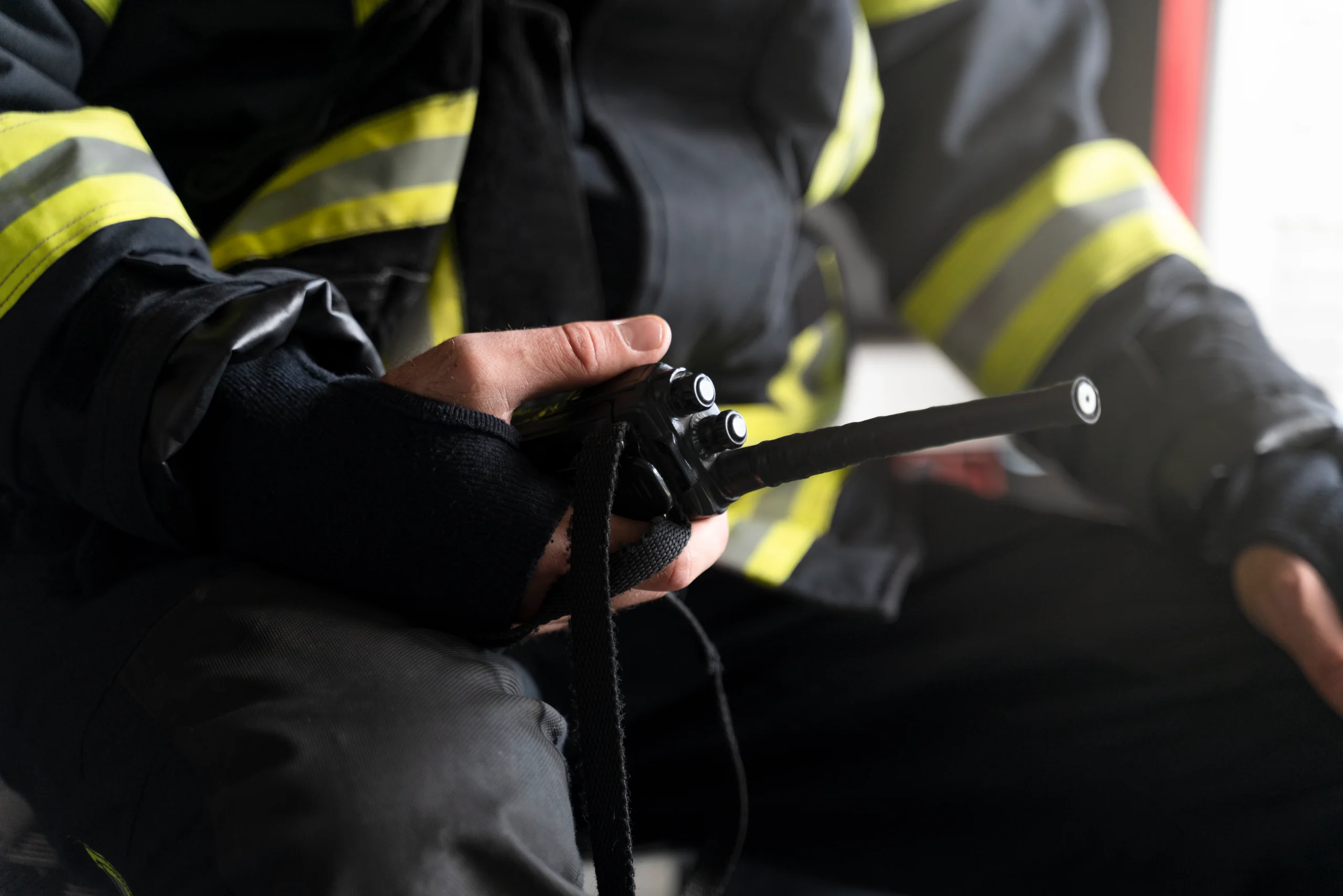 A man dressed in firefighter uniform holding a radio in his hand